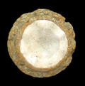 Clear conical faceted glass jewel in a copper alloy setting with a decorative rim from 18CV91 Smith St. Leonard Site.